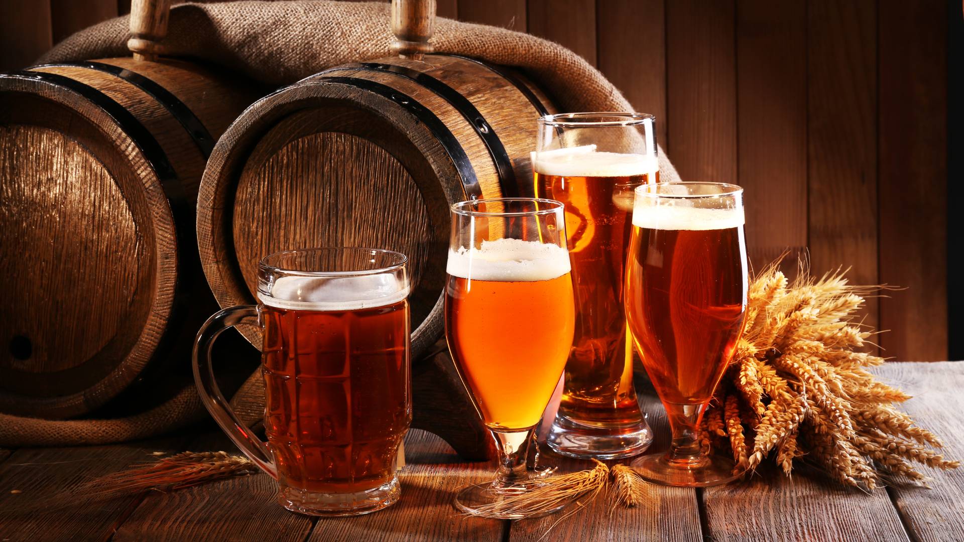glasses of beer next to wooden barrels